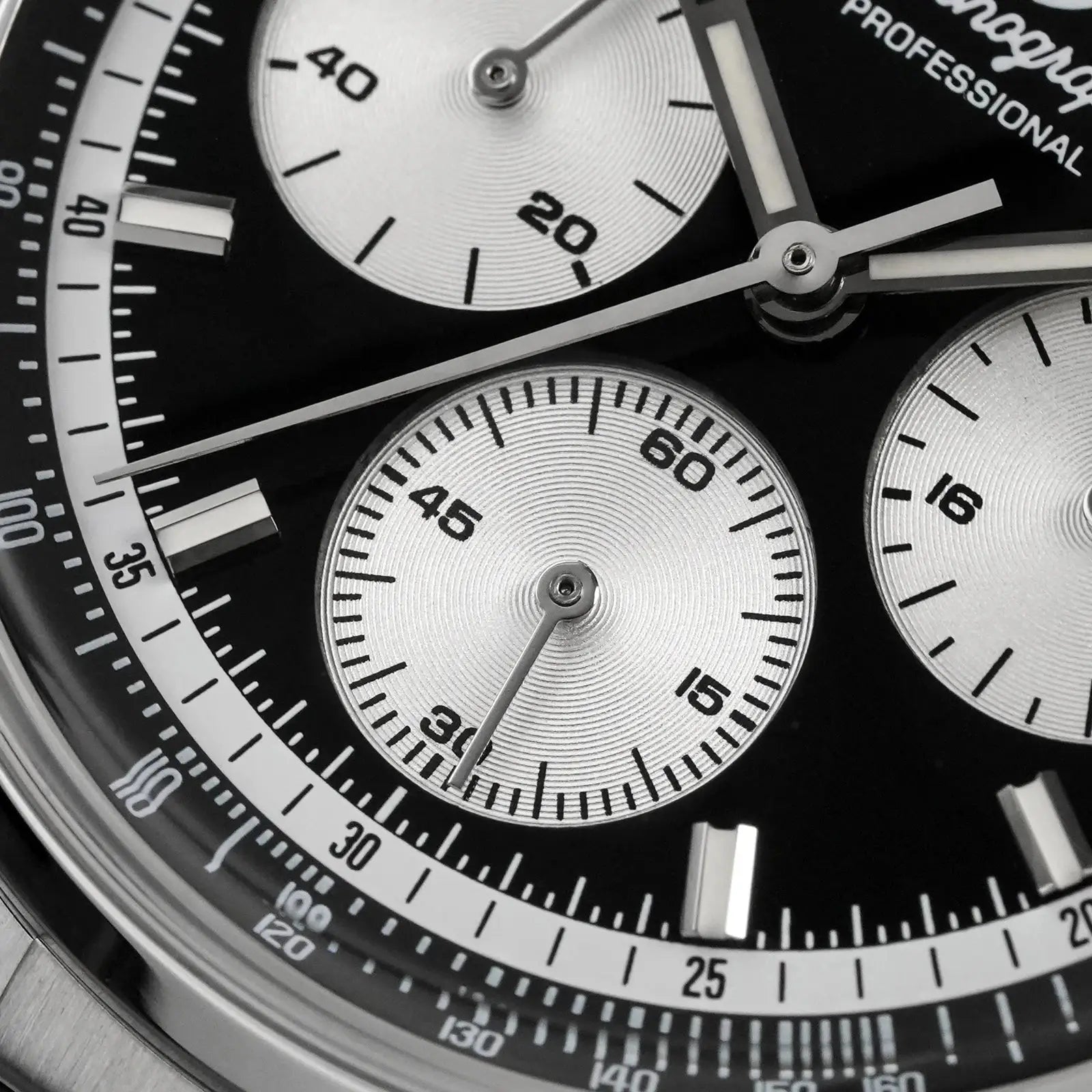 Watch dial close-up of a stainless steel chronograph with silver subdials, black face, and tachymeter bezel