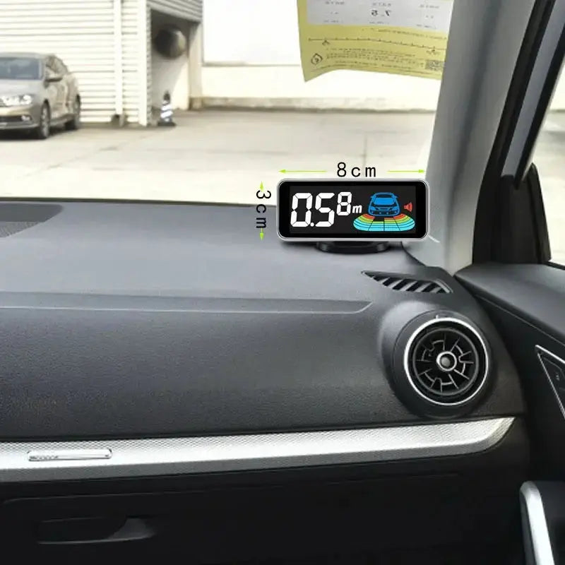 Parktronic parking sensor display mounted on car dashboard; compact black unit with digital readout
