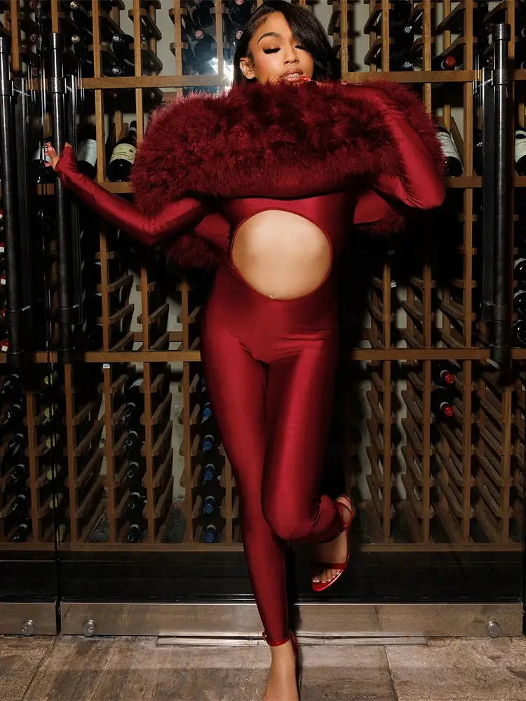 Sisterlinda Furry Slash Neck Jumpsuit; red metallic fabric with large circular midriff cutout and burgundy fur wrap