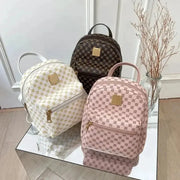 Classic women backpack fashion set: three bags in white, pink and brown with gold hardware, shown on a mirrored display