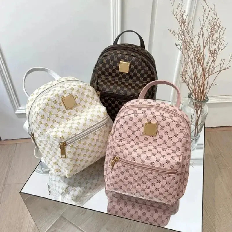Classic women backpack fashion set: three bags in white, pink and brown with gold hardware, shown on a mirrored display