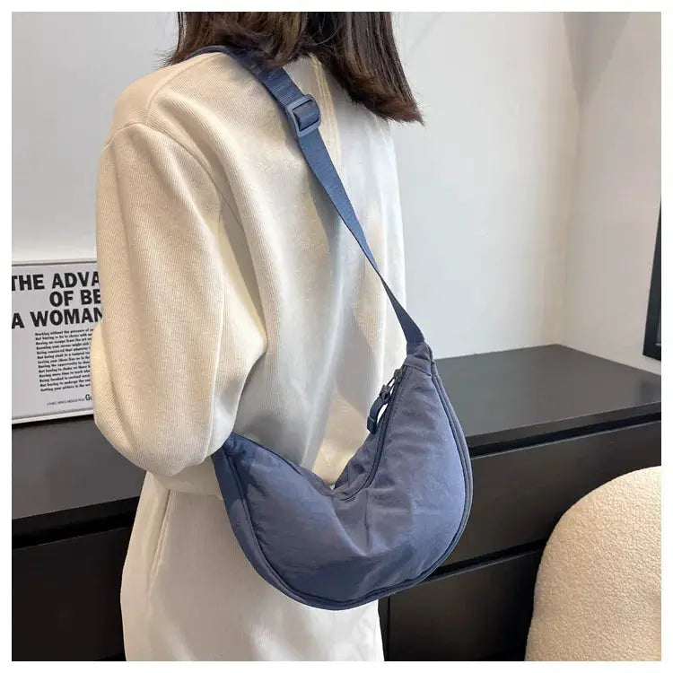 Casual nylon hobo crossbody bag in blue with adjustable strap worn by a woman.