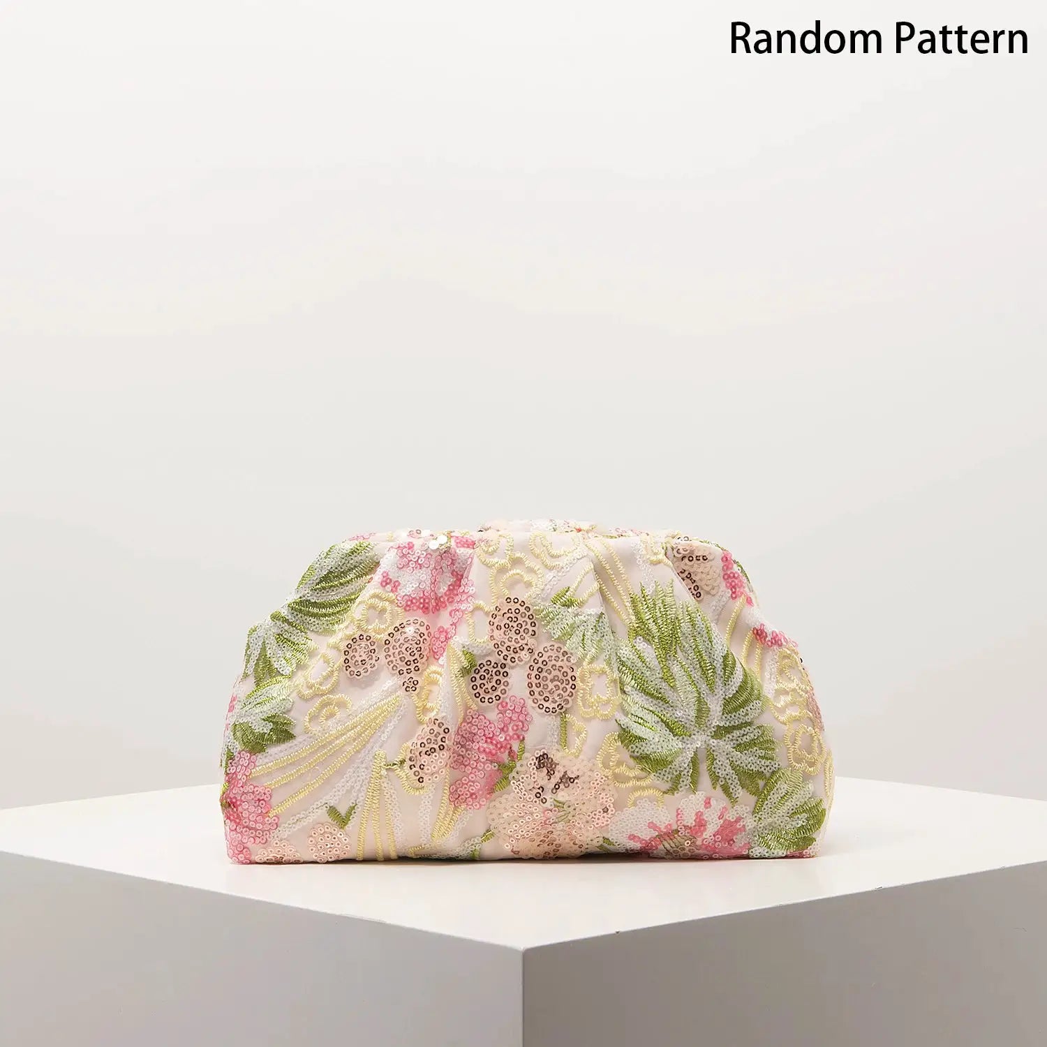 Clutch bag with floral sequined embroidery in pink and green on light fabric, displayed on a pedestal