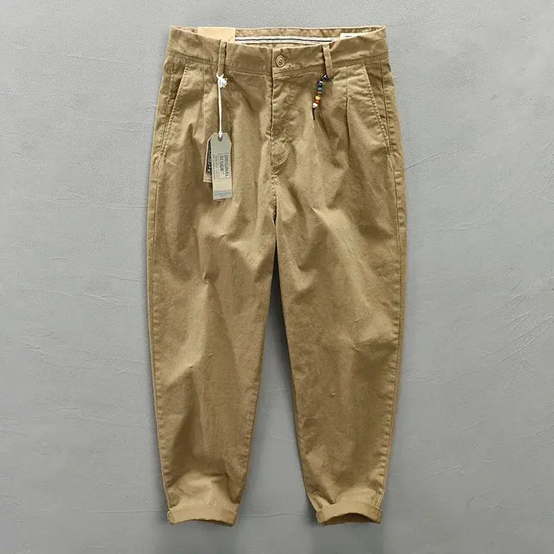 Khaki men's cotton cargo pants with belt, loose mid-rise fit, rolled cuffs, tag and bead keychain attached.