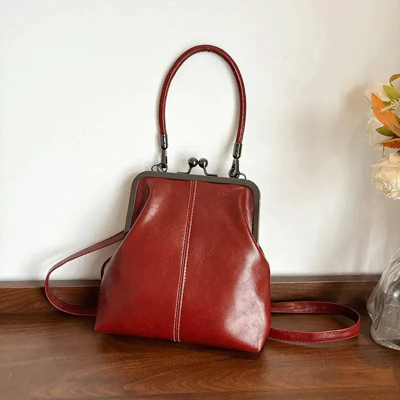 Vintage style women's handbag in brown PU leather with metal frame clasp, top handle and crossbody strap.