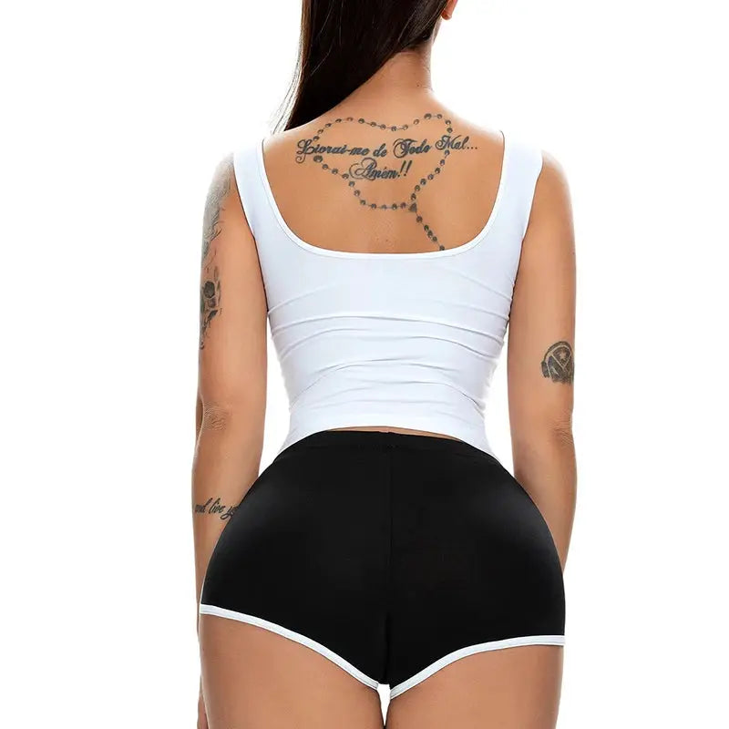 Womens black athletic shorts with white trim, back view on model wearing a white tank top