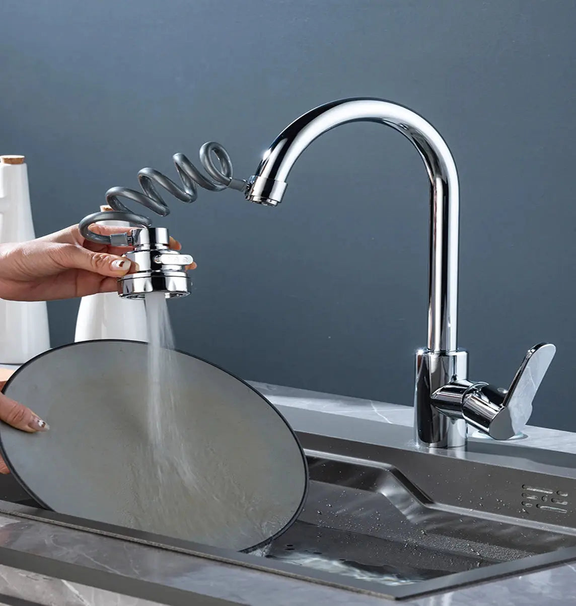 Chrome pull-out kitchen faucet with a coiled hose and spray head over a sink