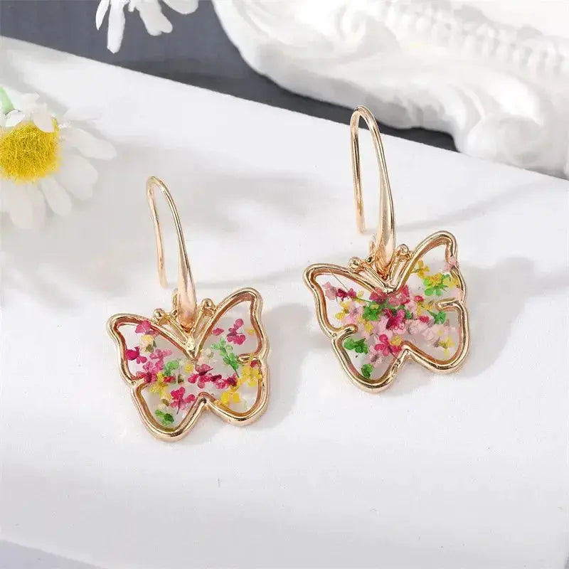 Pair of butterfly-shaped resin earrings with colorful pressed flowers on gold-tone hoops, Simples Market