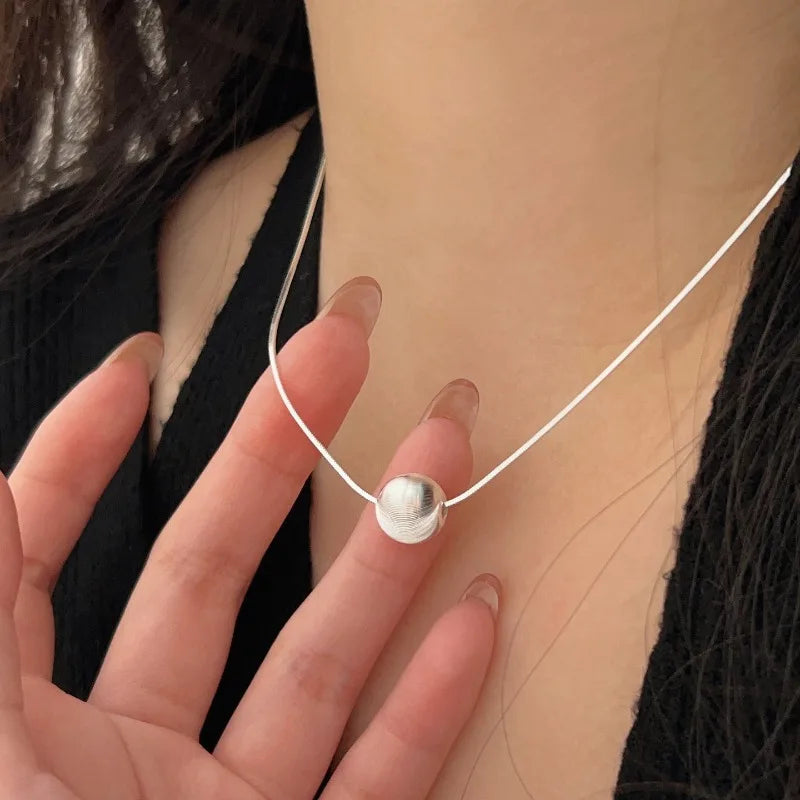 Sterling silver bead pendant necklace on a white cord; simple, elegant jewelry for women