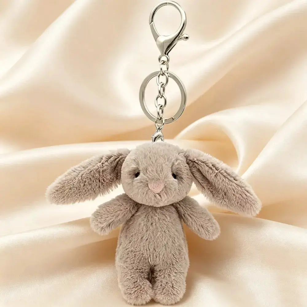 Plush rabbit keychain in beige-gray fabric with metal lobster clasp.