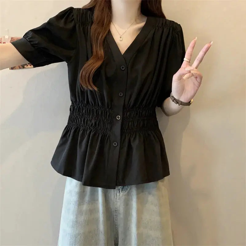 Black women's short-sleeve blouse with elastic smocked waist, V-neck, button-down front, peplum hem.