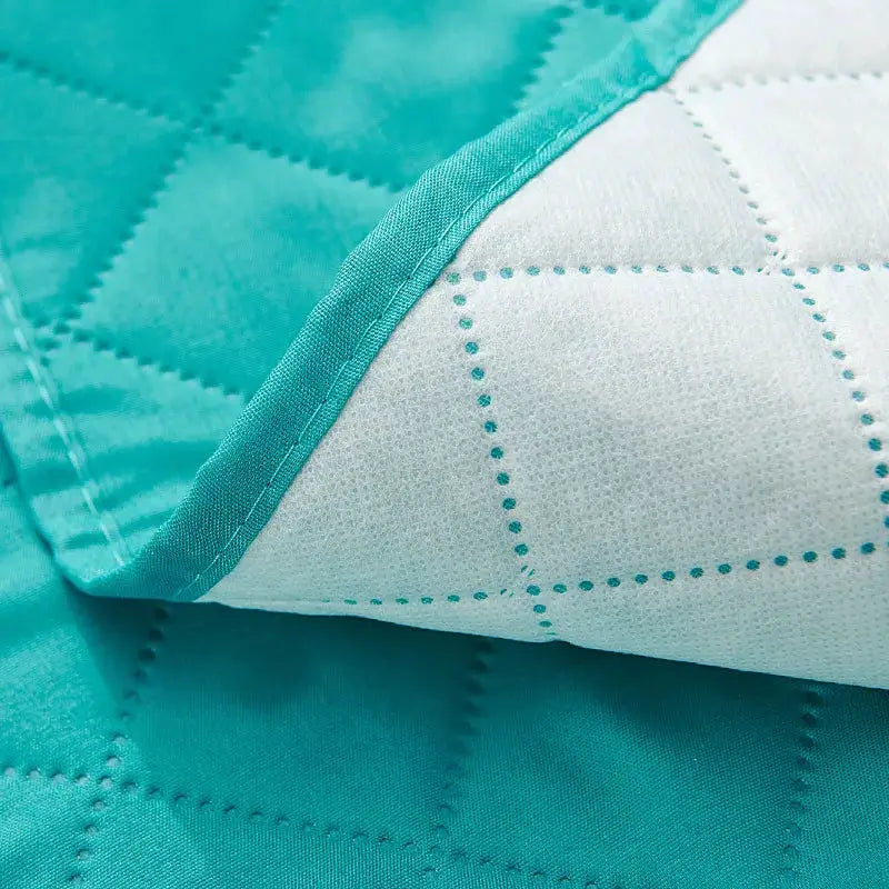 Anti-slip recliner chair cover in teal quilted fabric; solid color slipcover with grid-stitch pattern and teal underside.