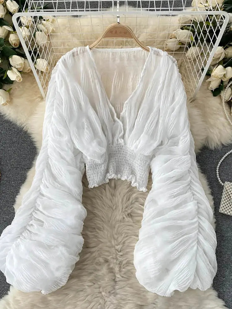 Draped white chiffon blouse with V-neck, puff long sleeves and cropped smocked waist.