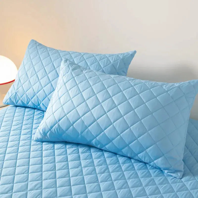 Blue quilted cotton pillowcases on a bed with a matching quilted sheet, for double-deck pillows.