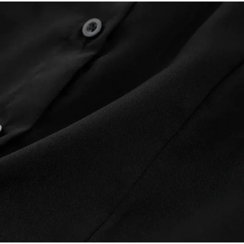 Women's black blouse close-up showing lapel and button detail on smooth fabric