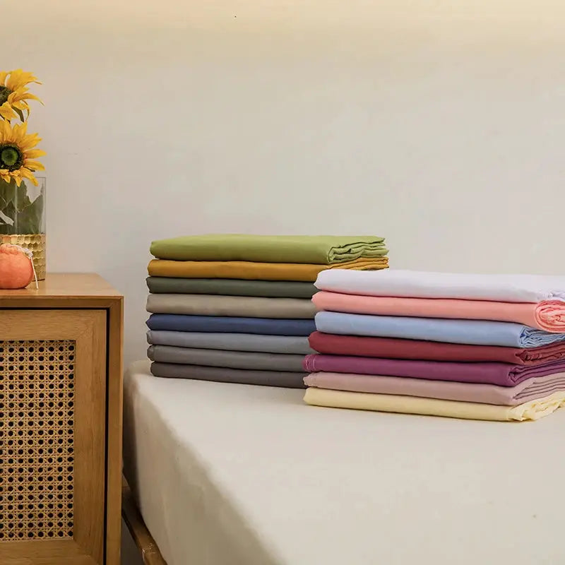Flat sheet for double bed, 1 pc, in assorted pastel colors, stacked on a bed