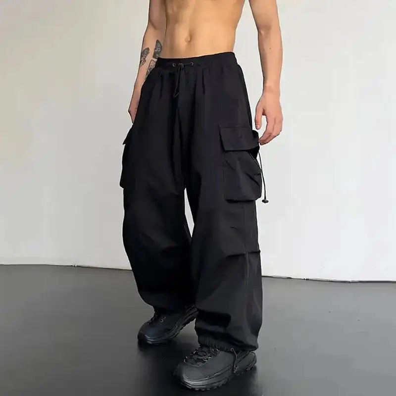 Men's cargo pants by Simples Market in black; loose wide-leg with cargo pockets and drawstring waist.