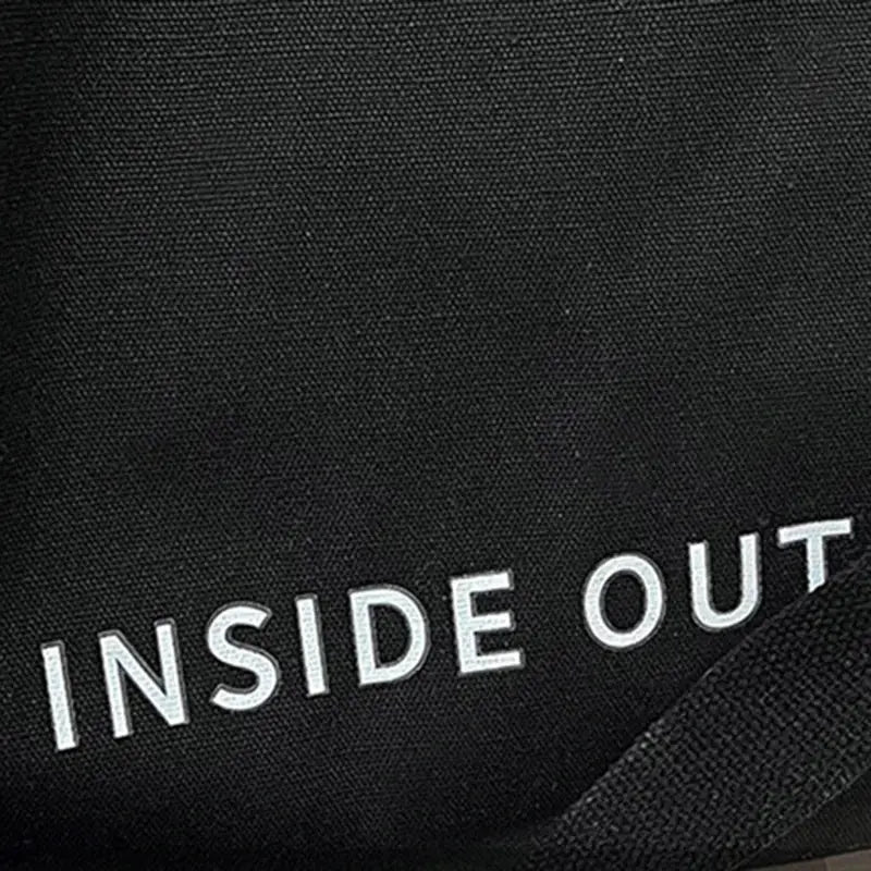 Canvas crossbody bag in black with INSIDE OUT text visible on fabric.