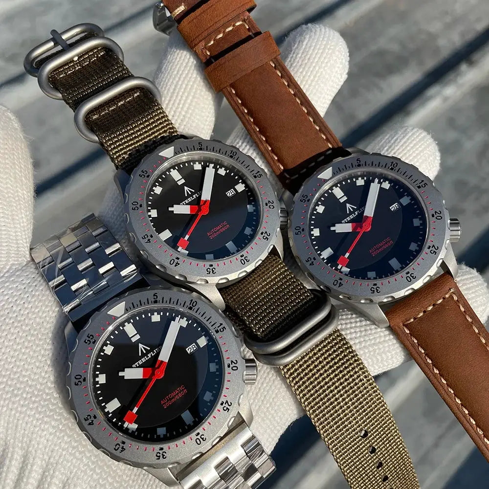 Three STEELFLIER SF752 wristwatches with black dials and red hands, on mixed straps (metal bracelet, NATO, leather)