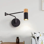 Modern black wall lamp with wood accent and adjustable cylindrical shade mounted on a circular base.