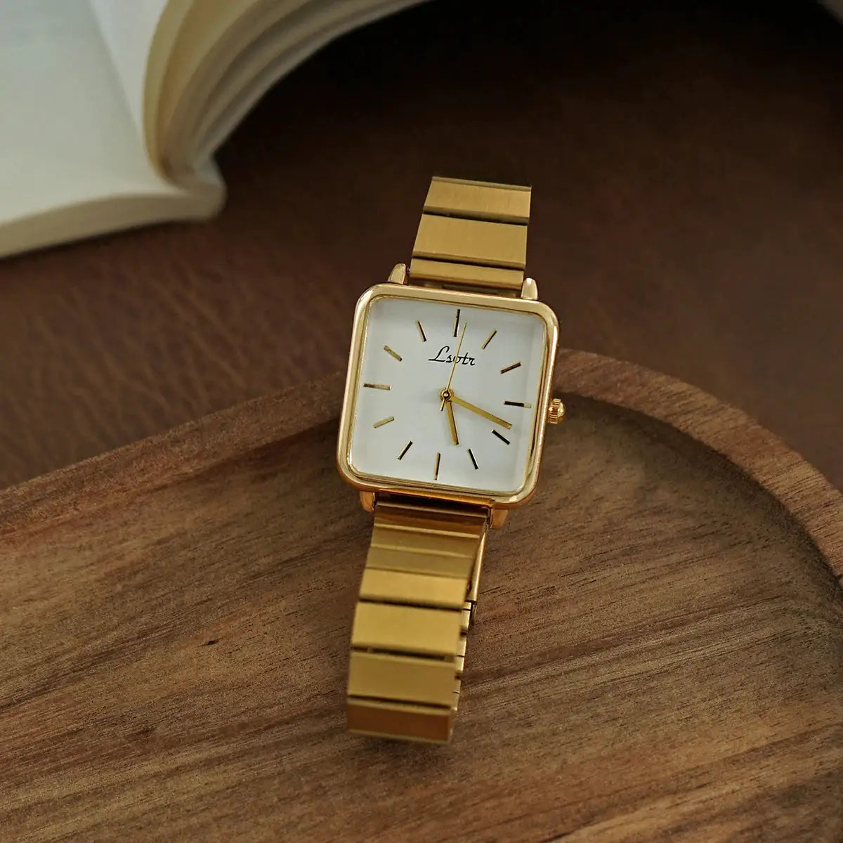 Gold women's square-dial wristwatch with a stainless steel band; Lustre logo on dial