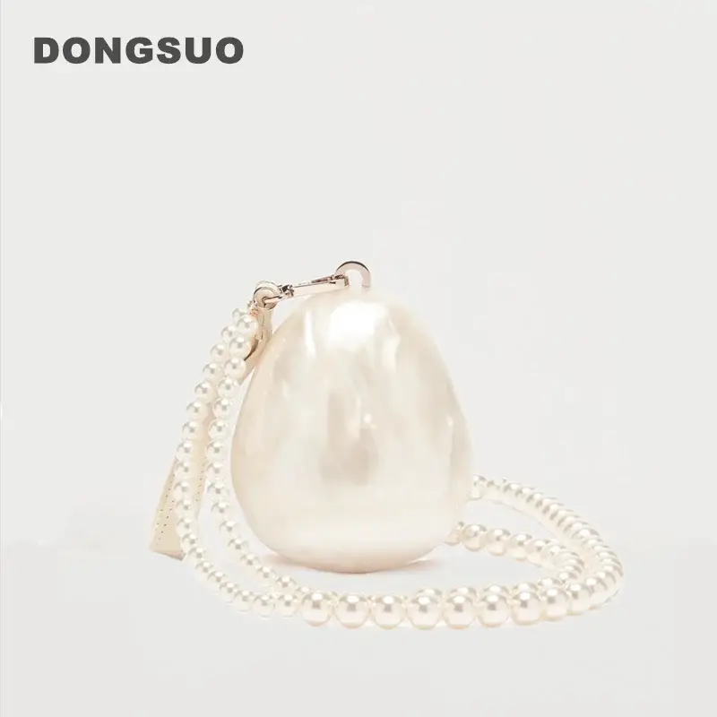 Egg-shaped pearl clutch bag with beaded strap in ivory, by DONGSUO