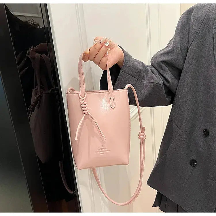 PU Leather Mini Crossbody Bag in pink with short top handle, long adjustable strap, and knot detail on the front.