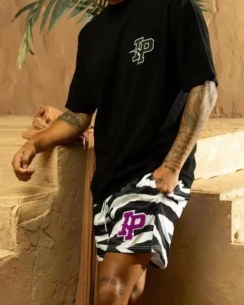 Men's athletic shorts with black-and-white zebra print and purple IP logo, paired with a black T-shirt.