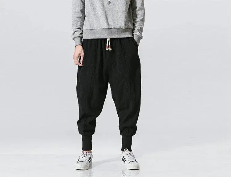 Men's cotton-linen harem pants in black with baggy drop-crotch style and cuffed ankles.