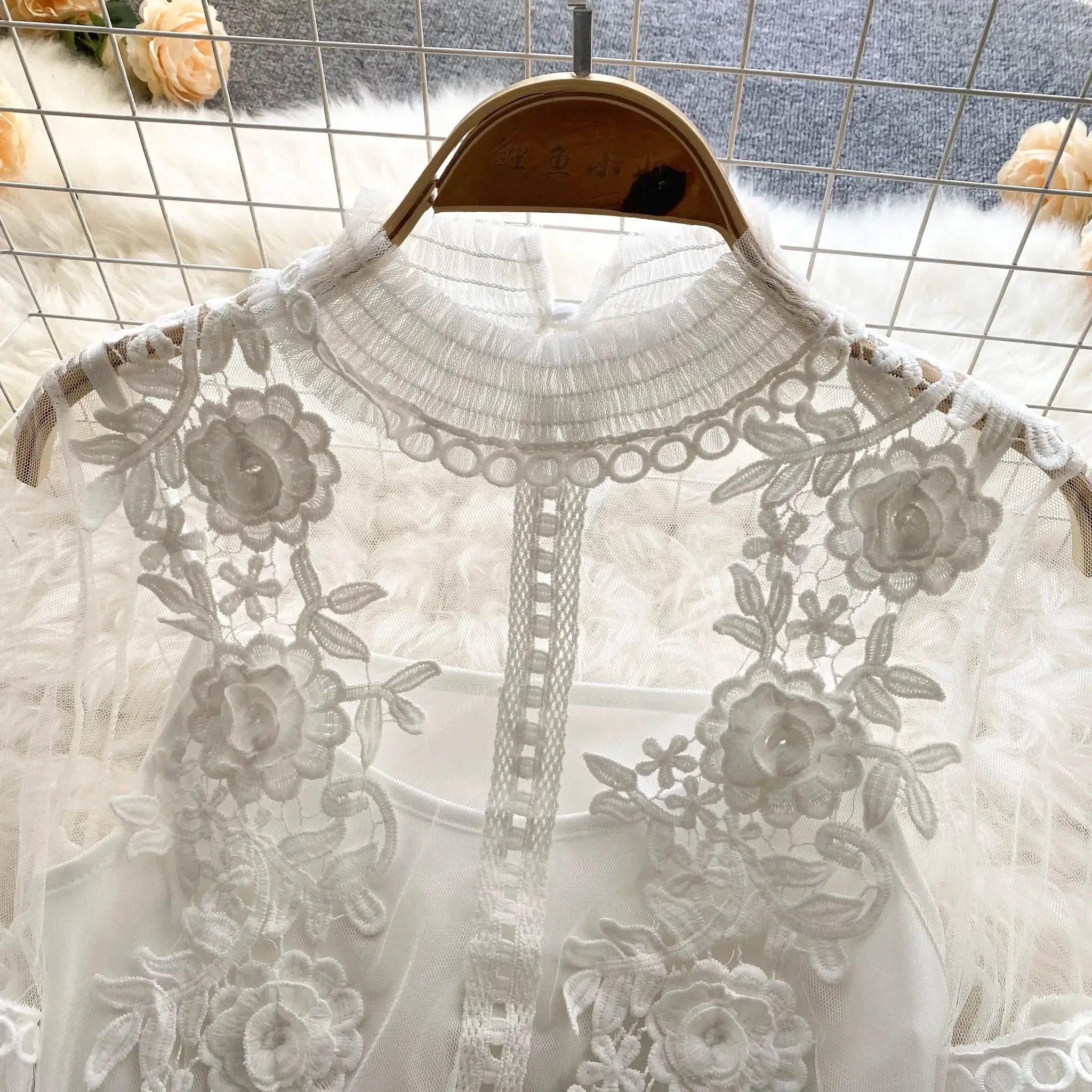 White lace puff-sleeve blouse with high neckline on wooden hanger