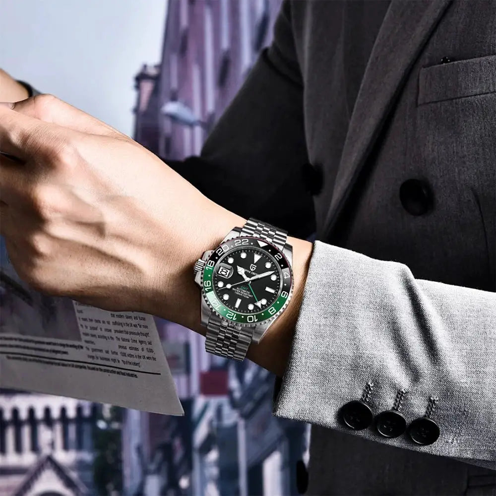 Pagani Design 40mm GMT stainless steel watch with black dial, green bezel, and metal bracelet on a gray-suited wrist.