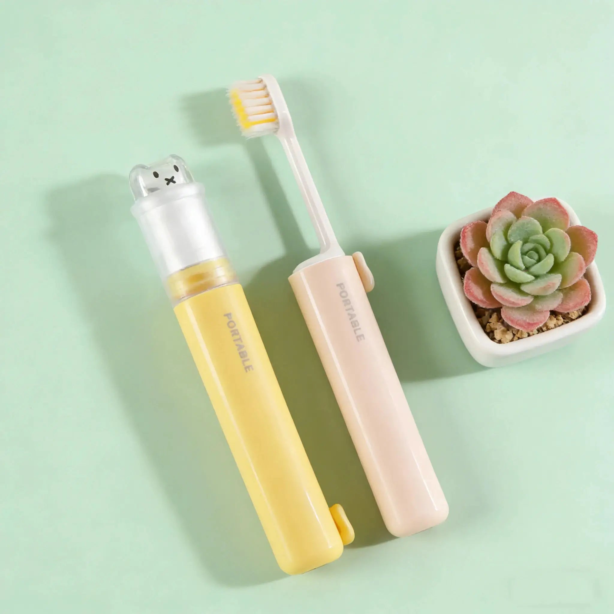 2-pack foldable travel toothbrushes with bear dust covers in pastel yellow and pink
