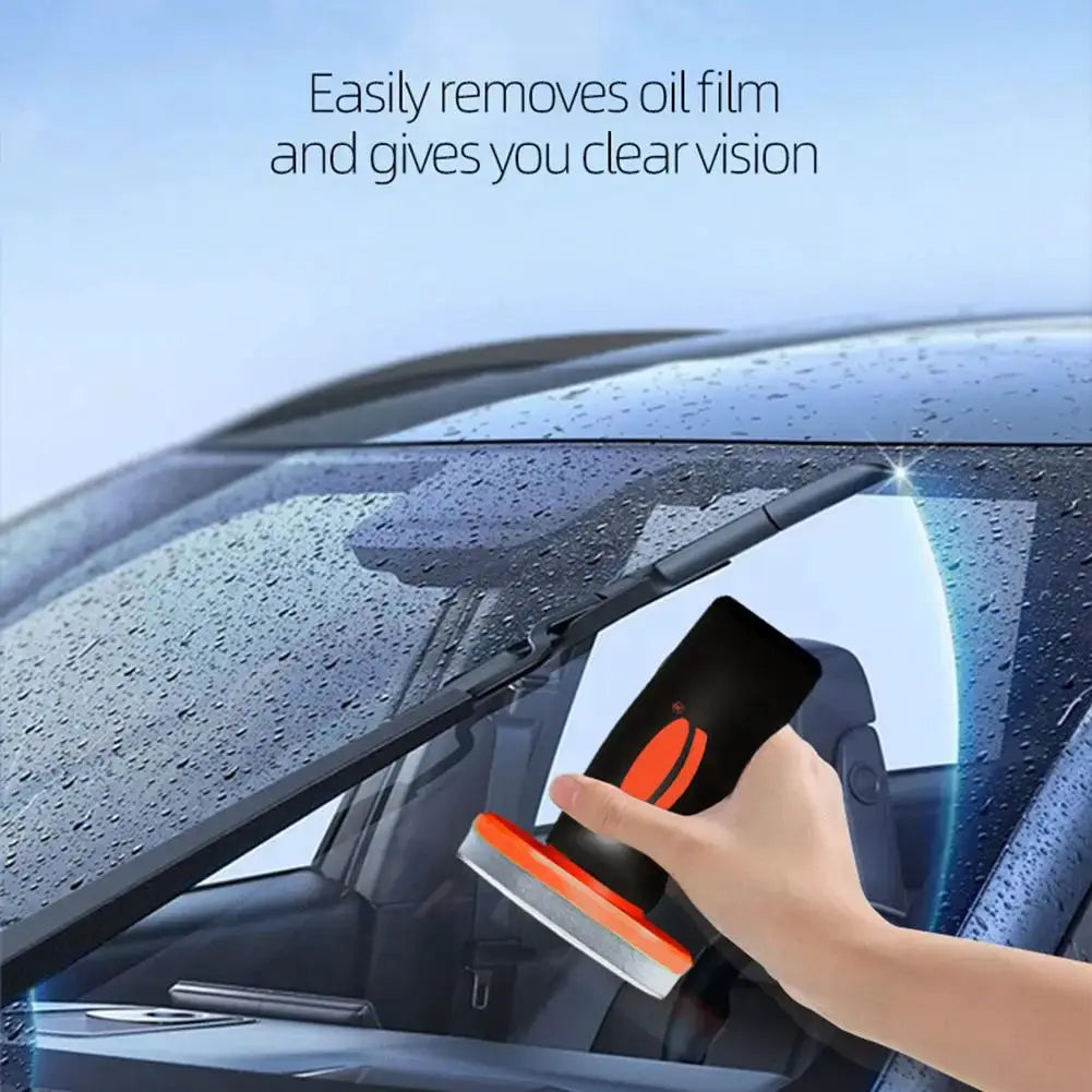 Simples Market 100g windshield cleaner and water repellent; black handheld applicator with orange accents on a wet car windshield
