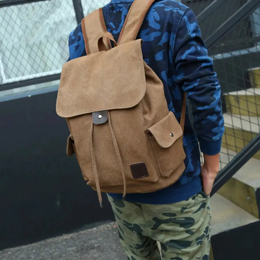 Brown canvas backpack with front flap, drawstring closure and side pockets