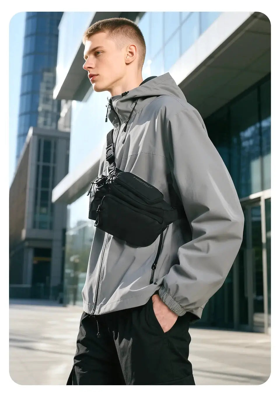 Tigernu chest bag crossbody, black nylon with multiple zip pockets worn across the chest by a man in a gray windbreaker