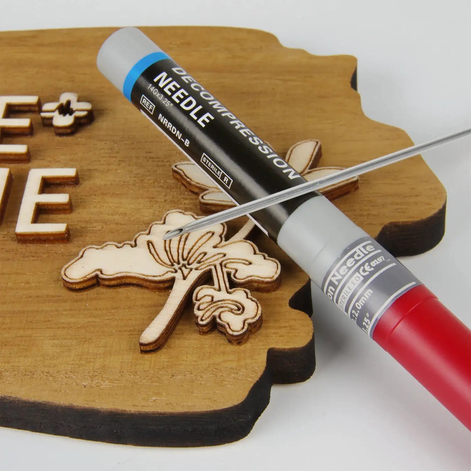 Needle decompression device by Simples Market, black body with blue ring and gray end cap on a wooden surface.