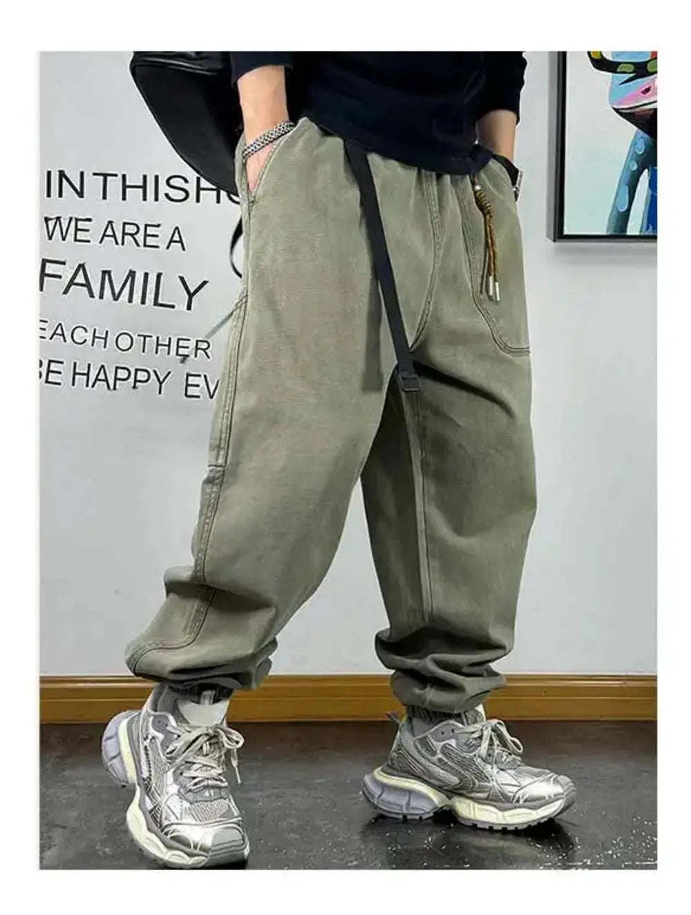 Baggy olive-green cargo pants with drawstring waist and multiple pockets, paired with chunky sneakers