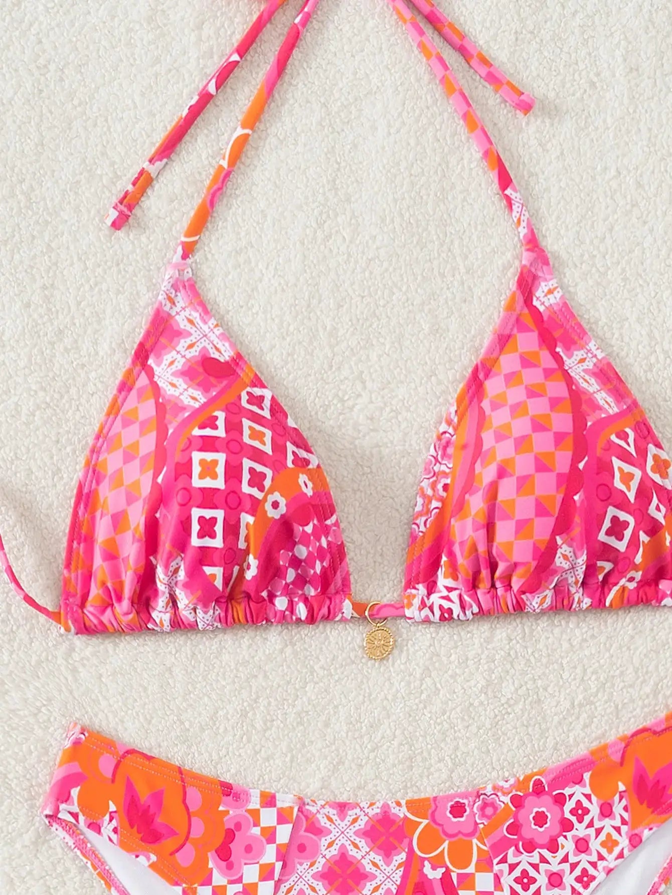 Triangle bikini set in pink and orange floral print with triangle top and Brazilian-cut bottom; bright summery vibe