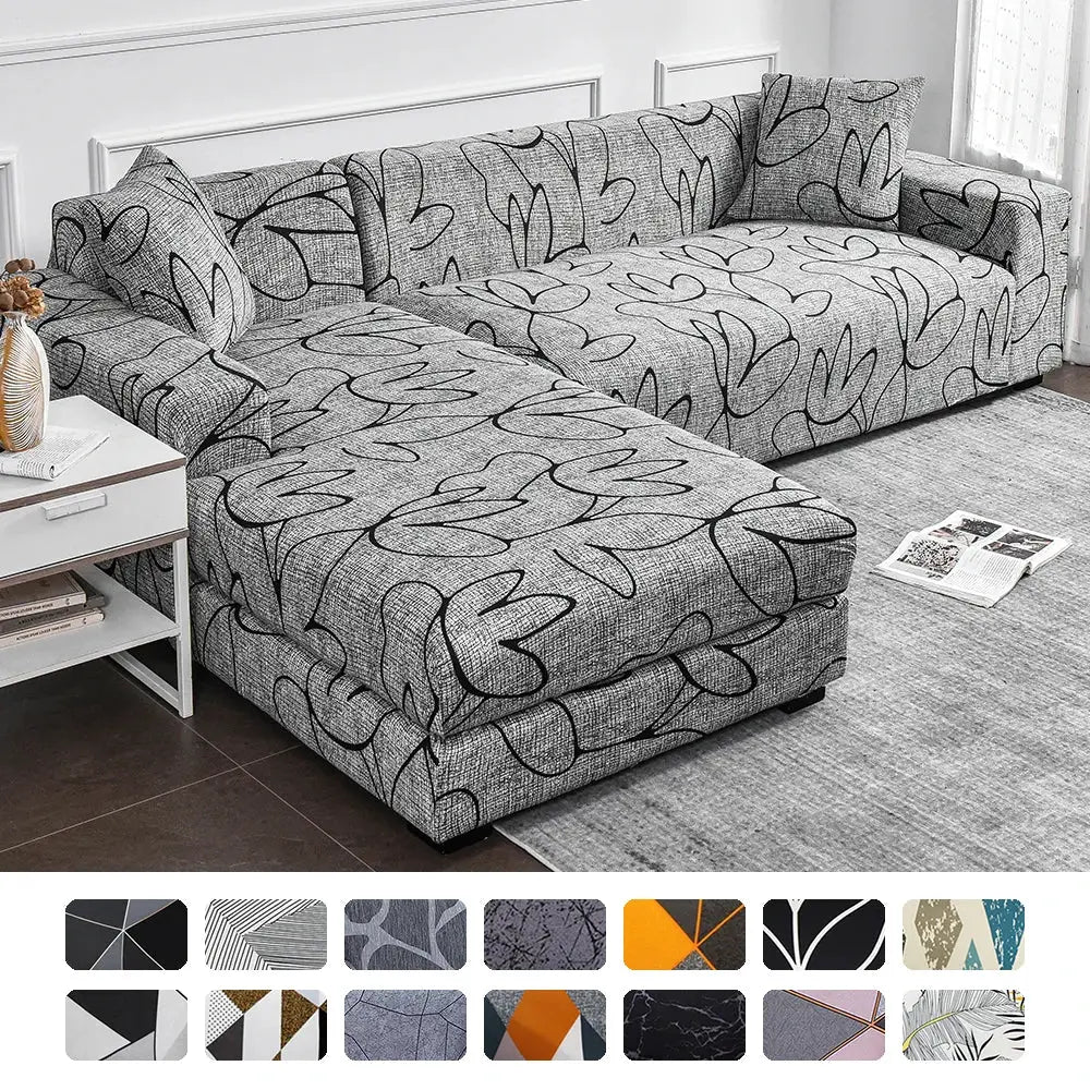 Elastic sofa slipcover for L-shaped sectional sofa, gray fabric with black abstract leaf print and cushions.