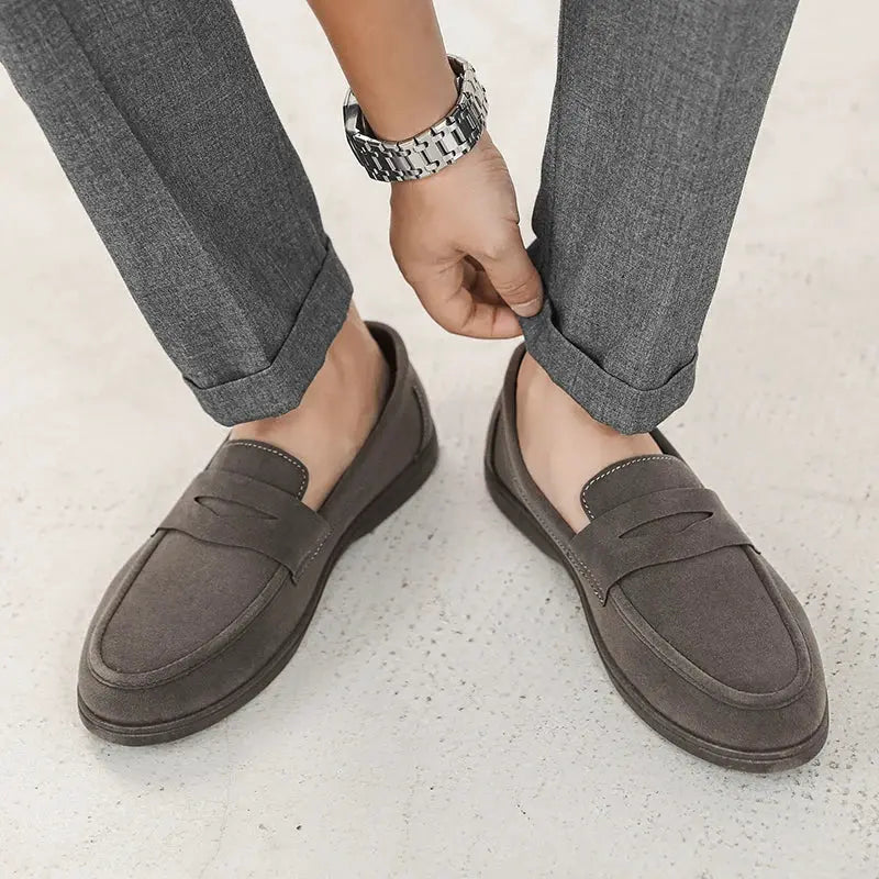 Pair of men's slip-on loafers in dark gray with stitched moccasin-style toe and soft sole.