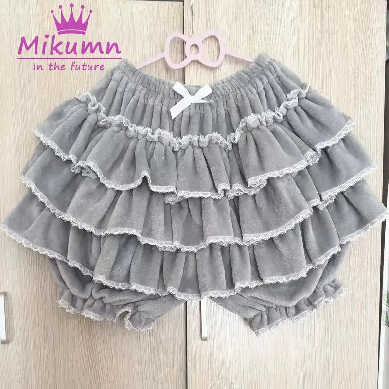 Gray layered ruffle shorts with white lace trim and bow; Mikumm watermark, Simples Market
