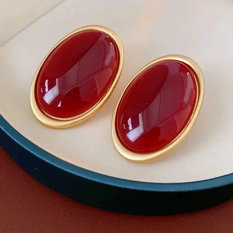 Pair of vintage red resin oval stud earrings with gold-tone bezel, large geometric design.