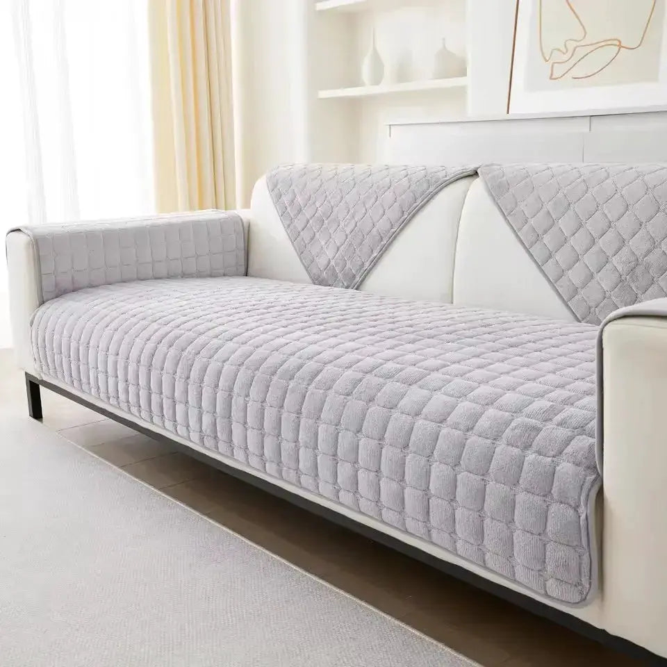 Gray quilted sofa cover for seat and backrest on a white sofa; grid-pattern plush fabric