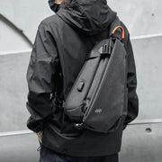 Anti-Theft crossbody sling bag by Simples Market in gray with orange top handle