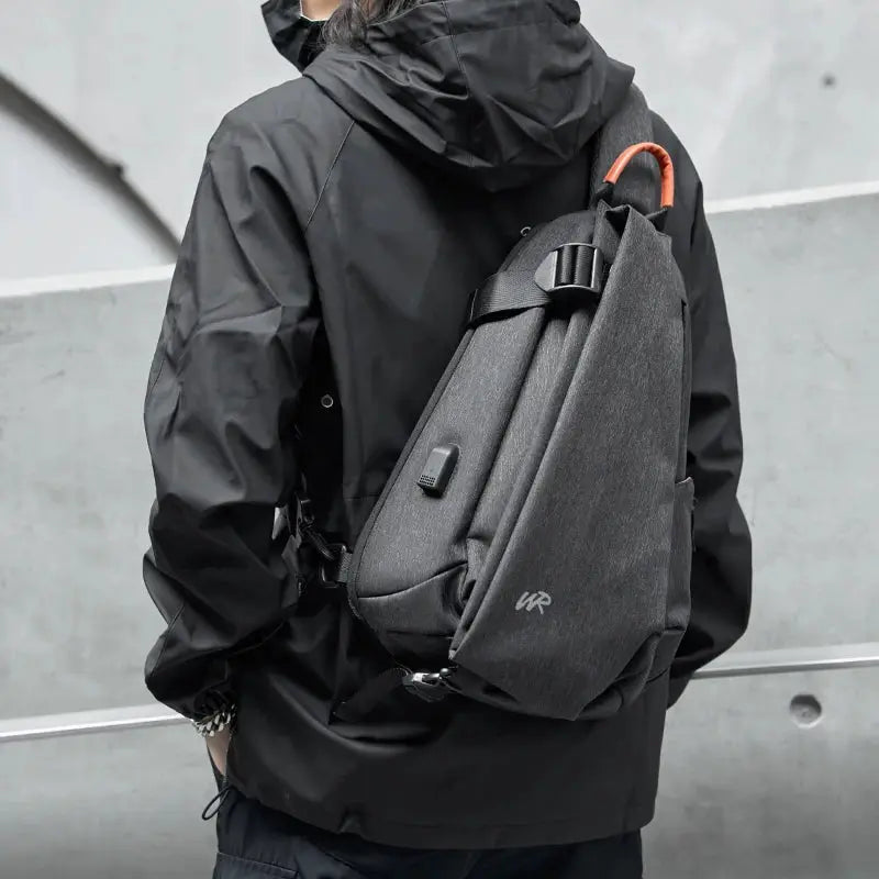 Anti-Theft crossbody sling bag by Simples Market in gray with orange top handle