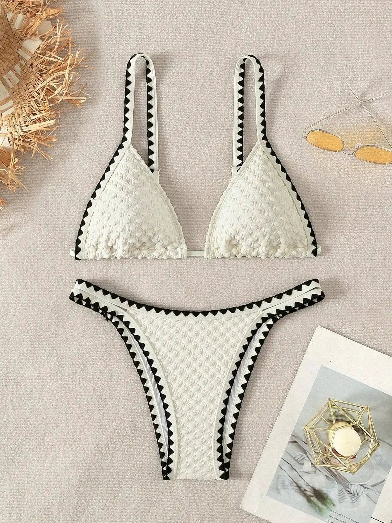 White textured two-piece bikini with black zigzag trim; bandeau-style top and high-cut bottoms.