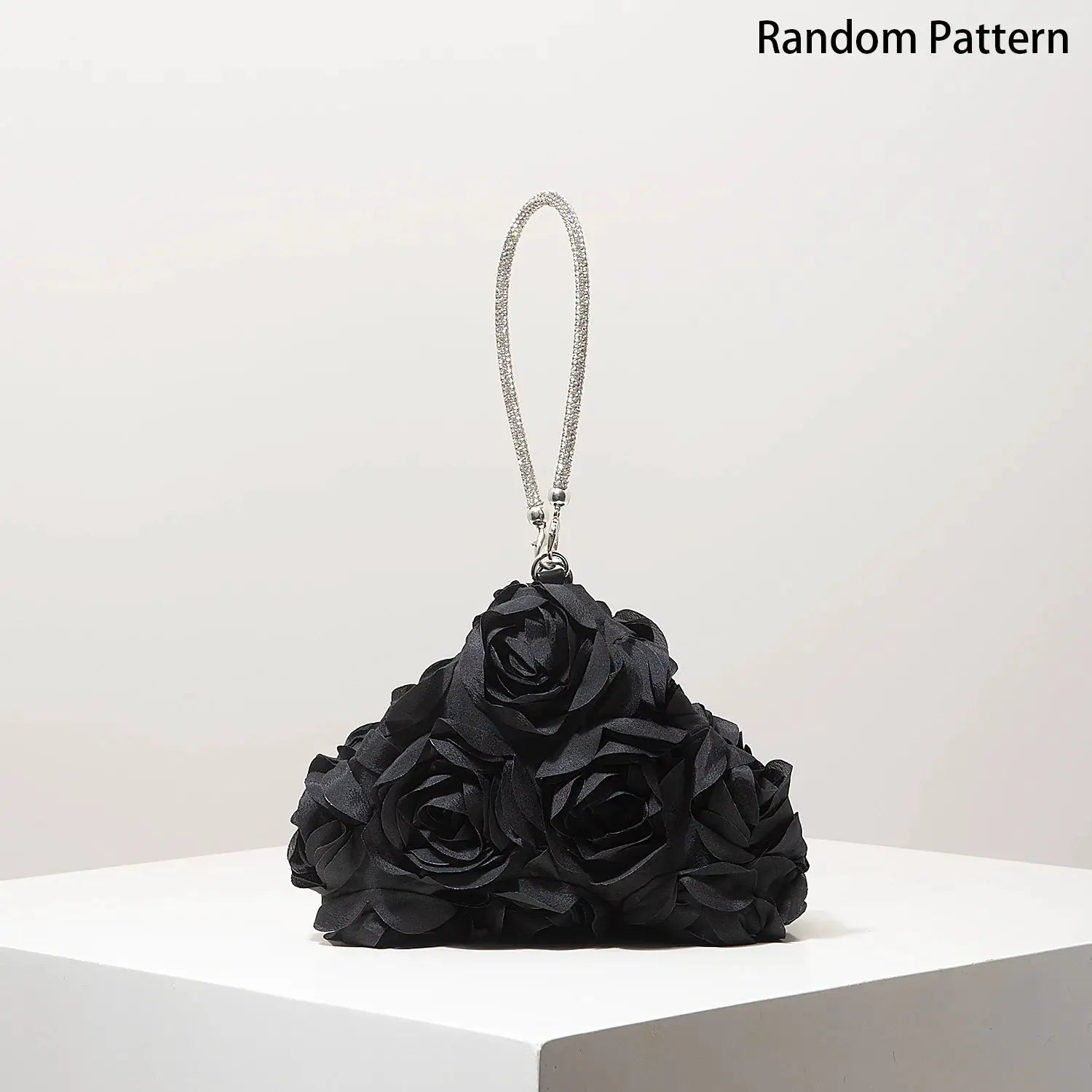 Mini purse with sparkling rhinestone strap atop a black rosette floral bag by Simples Market
