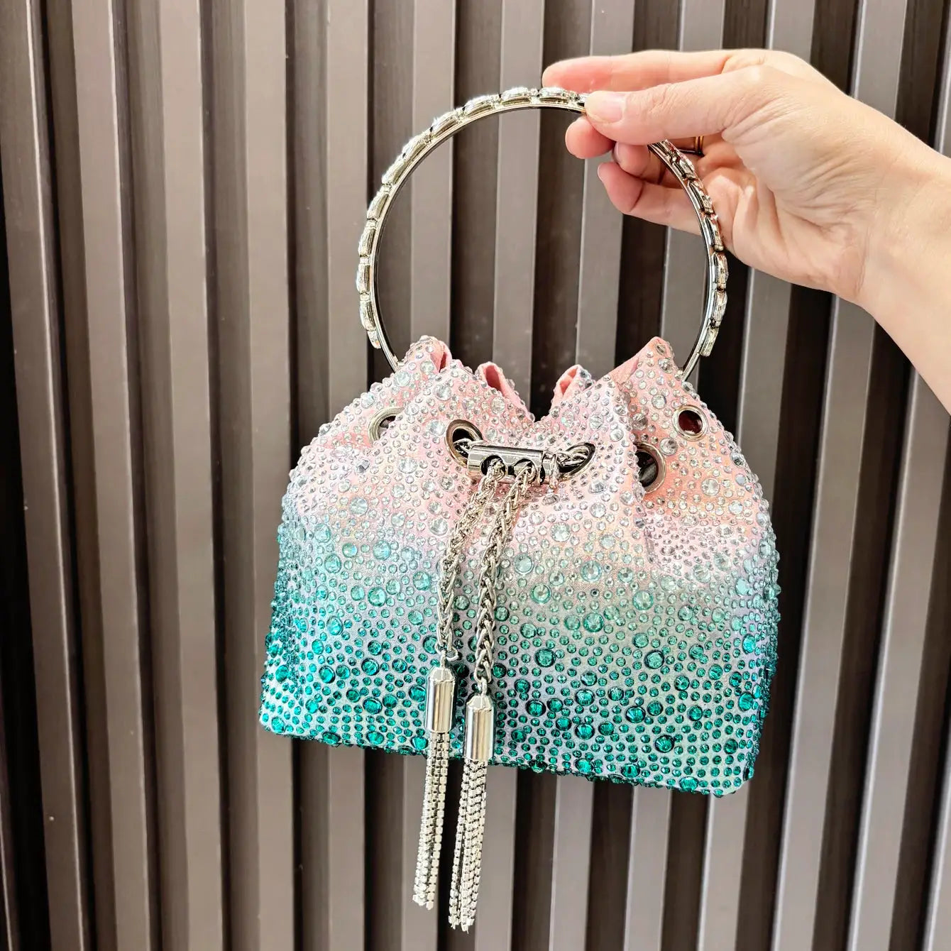Simples Market rhinestone evening clutch with gradient pink-to-teal crystals and a round jeweled metal handle bucket bag.