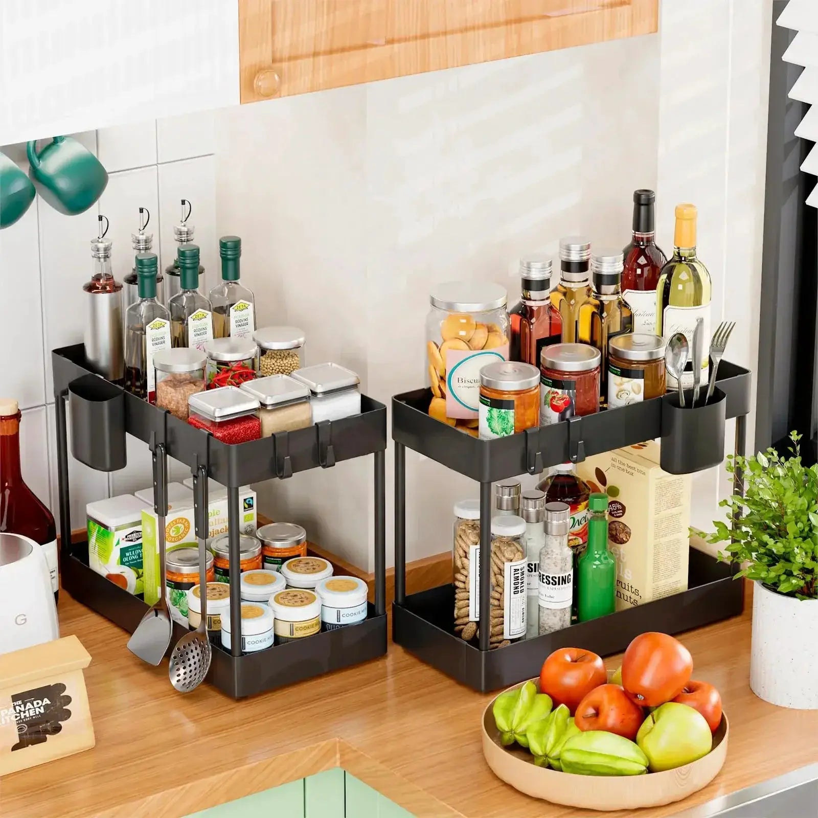 Two black 2-tier under-sink sliding cabinet organizers with hooks, holding bottles, jars and canisters.