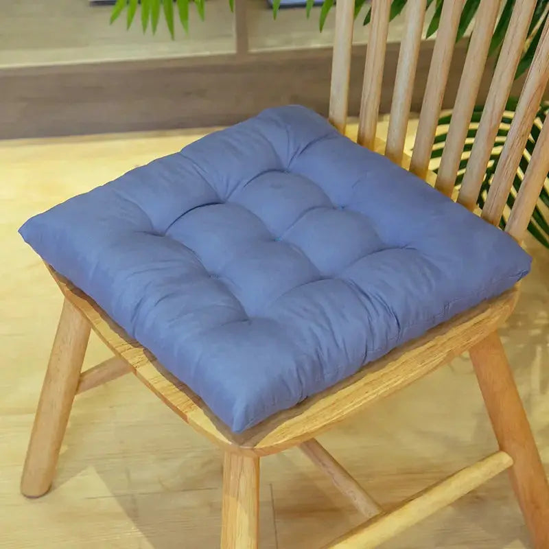 Chair cushion, blue tufted square with ties on a wooden dining chair.